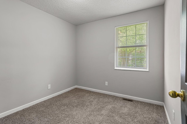 carpeted spare room with a textured ceiling, visible vents, and baseboards