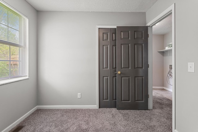 unfurnished bedroom featuring carpet floors, a textured ceiling, baseboards, and a closet