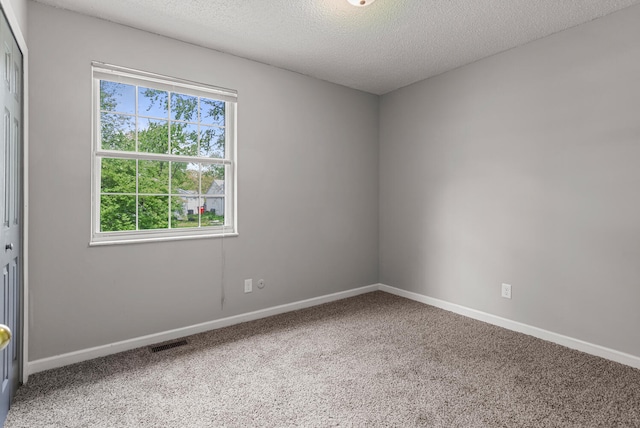 carpeted empty room with baseboards, a textured ceiling, and visible vents