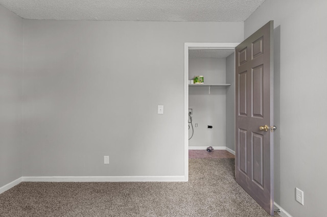 washroom featuring baseboards, dark colored carpet, and a textured ceiling