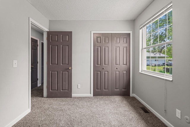 unfurnished bedroom with a textured ceiling, carpet, and a closet