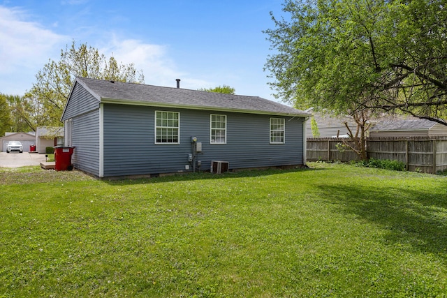 rear view of property featuring central AC unit, fence, and a yard