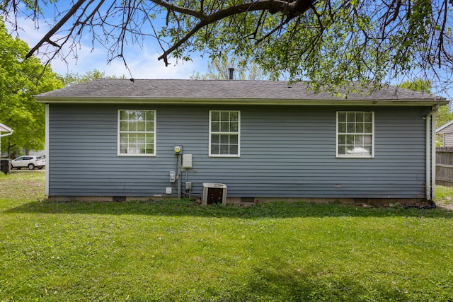 rear view of property featuring central AC unit, fence, and a yard