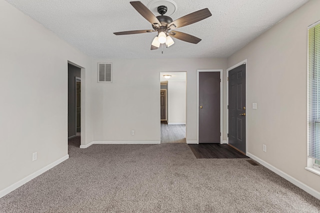 unfurnished room with a ceiling fan, a textured ceiling, visible vents, baseboards, and dark carpet