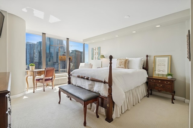 bedroom with recessed lighting, baseboards, light colored carpet, and a city view