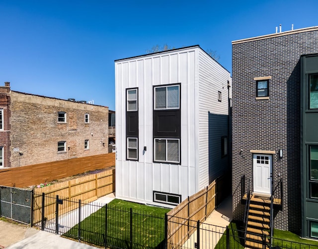 contemporary house featuring a fenced backyard, board and batten siding, and a front yard