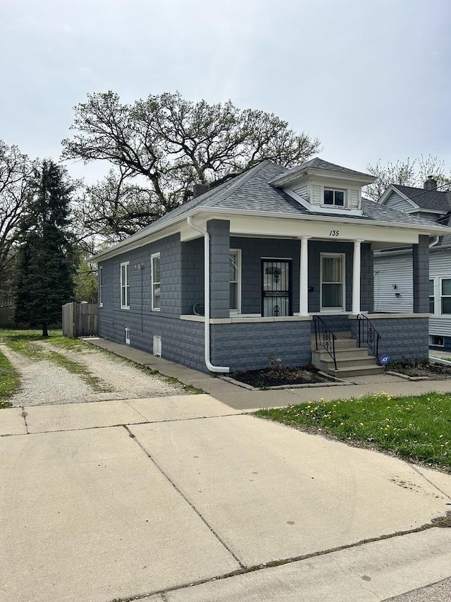 bungalow-style house with a porch and roof with shingles