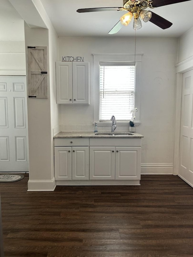 kitchen featuring dark wood-style flooring, a ceiling fan, baseboards, and a sink