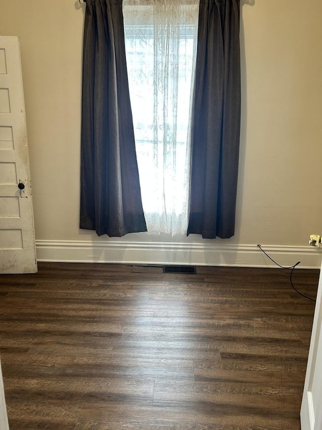 empty room with visible vents, baseboards, and wood finished floors