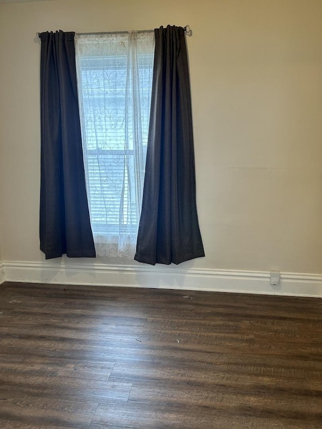 unfurnished room featuring baseboards and wood finished floors