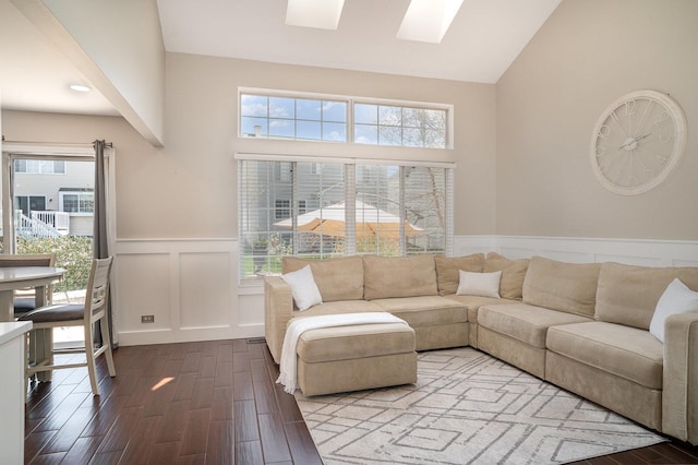 553 Ivory Ln, Bartlett, IL 60103 - living room featuring a skylight, wainscoting, high vaulted ceiling, dark wood-style floors, and a decorative wall
