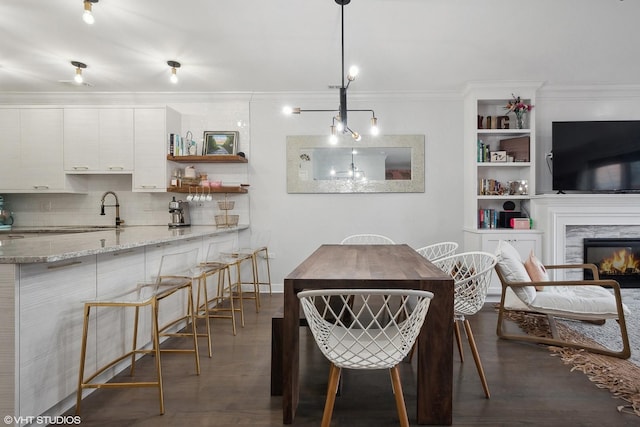 dining room with crown molding, built in features, a fireplace, and dark wood-style floors