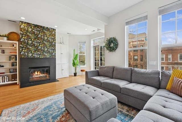 living room featuring a glass covered fireplace, recessed lighting, wood finished floors, and a healthy amount of sunlight