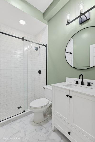 bathroom with vanity, marble finish floor, a stall shower, and toilet