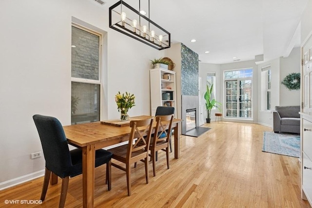 dining space featuring baseboards, light wood-style flooring, and a fireplace