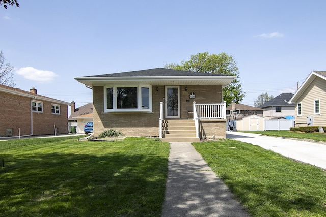 bungalow-style home featuring brick siding, a storage unit, covered porch, and a front yard