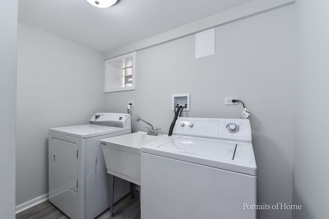washroom with laundry area, a sink, washing machine and dryer, and wood finished floors