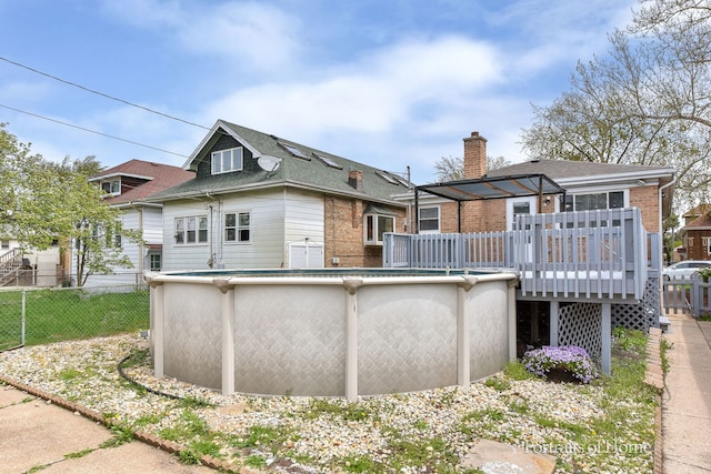 back of house with brick siding, fence, a deck, and a fenced in pool