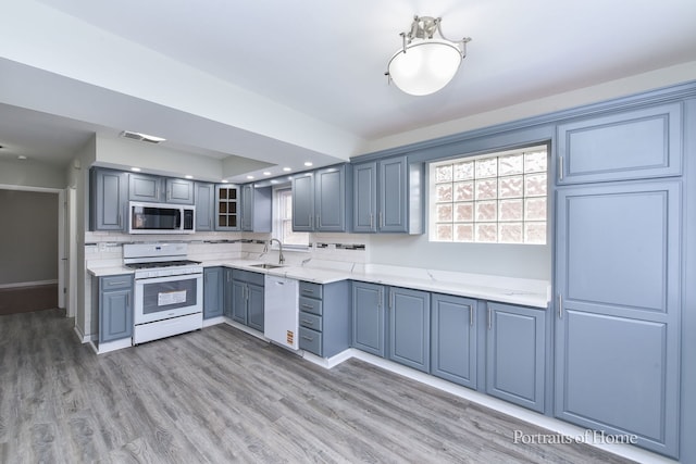 kitchen with white appliances, visible vents, a healthy amount of sunlight, and a sink