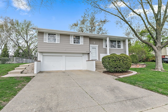 bi-level home with concrete driveway, brick siding, a front lawn, and a garage