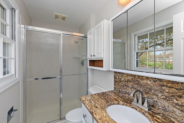 bathroom featuring visible vents, toilet, and a shower stall