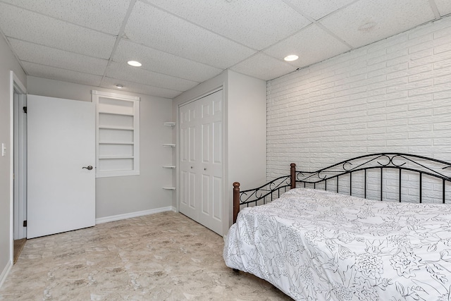 bedroom with baseboards, a closet, recessed lighting, and a paneled ceiling