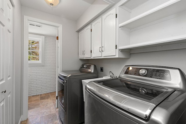 washroom featuring cabinet space, stone finish floor, washer and clothes dryer, and visible vents