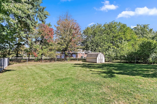 view of yard with a storage shed, fence, and an outbuilding