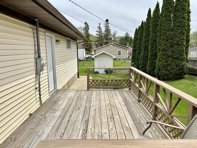 wooden deck featuring an outdoor structure, a lawn, and a storage unit