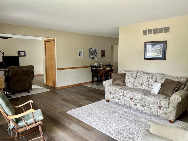 living room featuring visible vents, baseboards, and wood finished floors