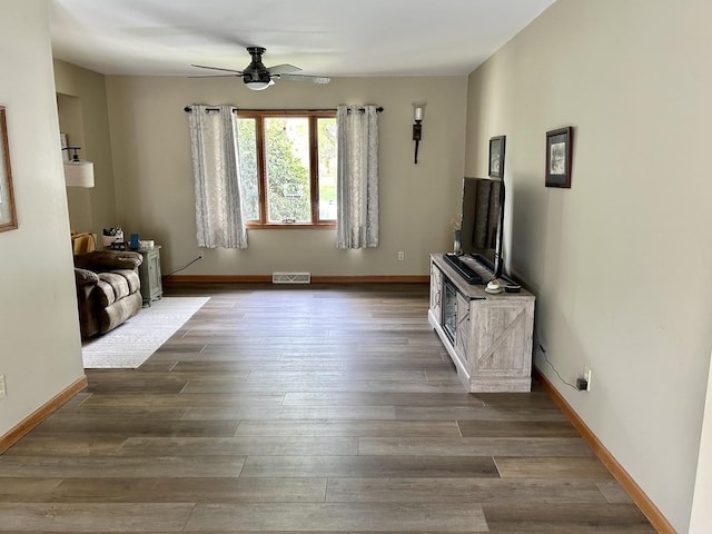 living area featuring baseboards, ceiling fan, wood finished floors, and visible vents