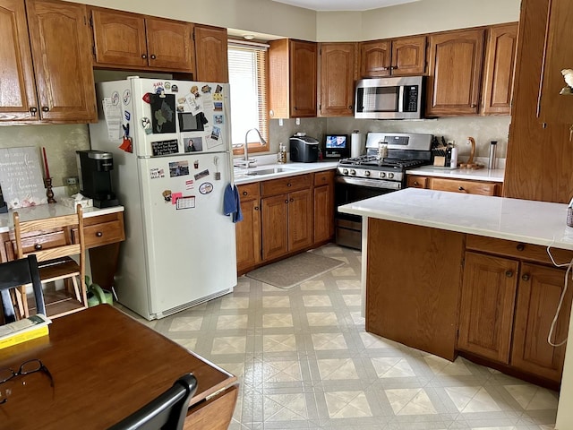kitchen featuring a sink, light floors, appliances with stainless steel finishes, and brown cabinets