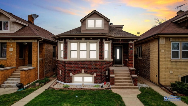 bungalow-style home with brick siding and a shingled roof