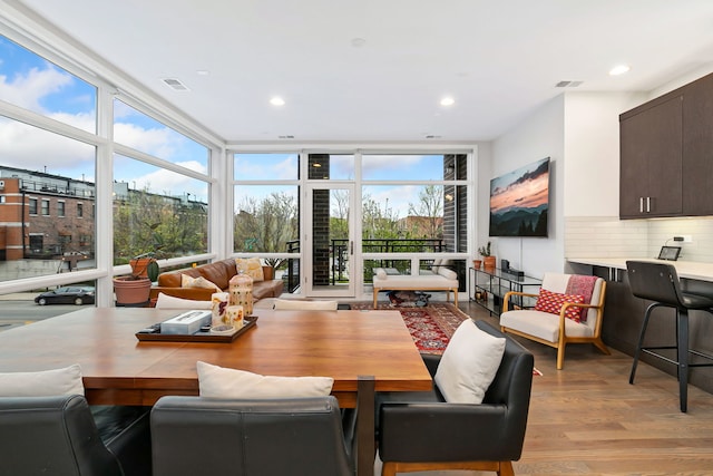 dining room with a wall of windows, a healthy amount of sunlight, light wood finished floors, and visible vents