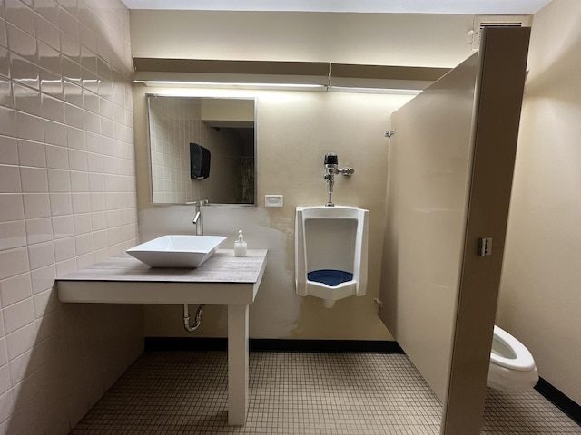 bathroom with a sink, tile walls, tile patterned flooring, and toilet