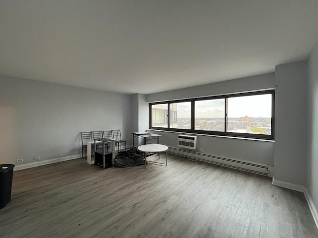 dining area with baseboards, a baseboard radiator, a wall unit AC, and wood finished floors
