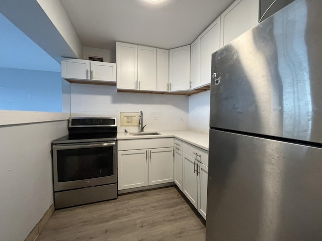 kitchen featuring appliances with stainless steel finishes, white cabinetry, a sink, light countertops, and light wood-style flooring