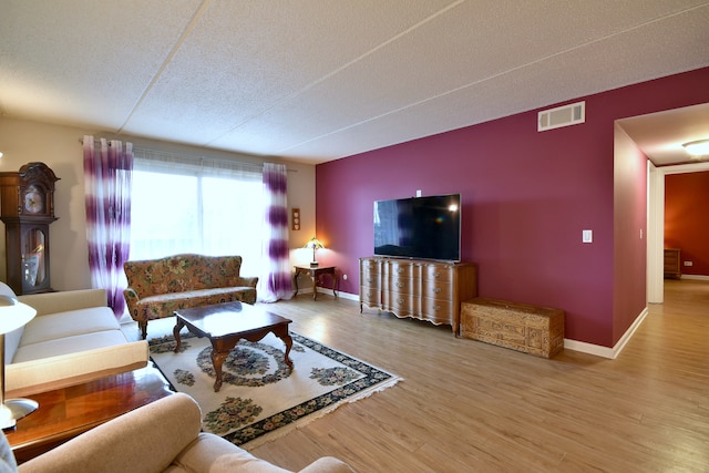living area featuring visible vents, baseboards, a textured ceiling, and wood finished floors
