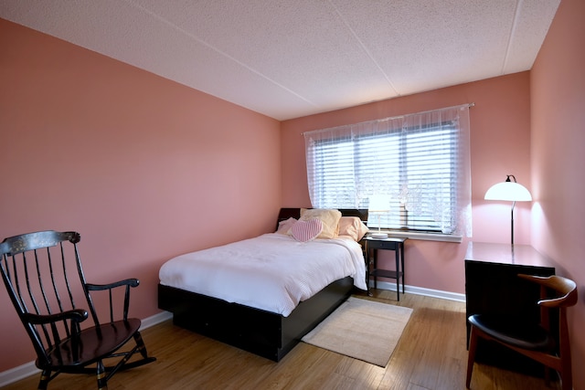 bedroom with baseboards, a textured ceiling, and wood finished floors