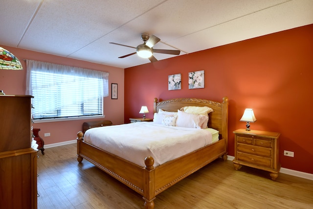bedroom with baseboards, a ceiling fan, and light wood finished floors