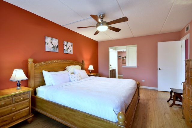 bedroom with a ceiling fan, baseboards, visible vents, and wood finished floors