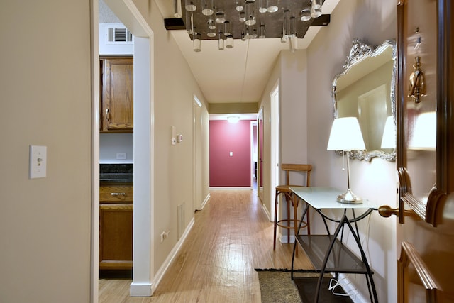 corridor featuring light wood-style floors, baseboards, and visible vents