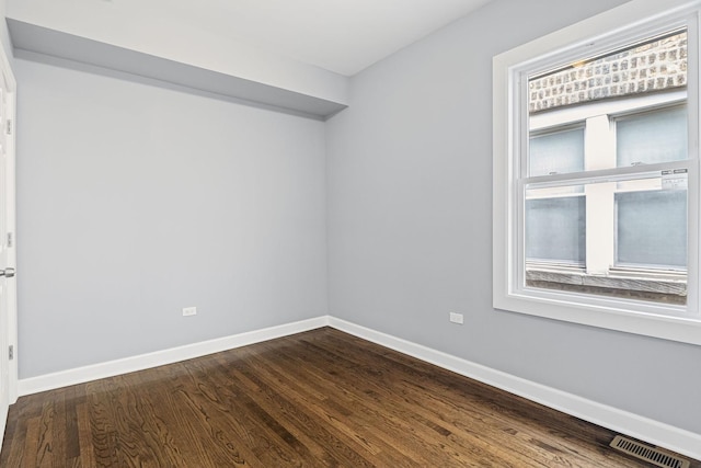 spare room featuring baseboards, visible vents, and dark wood-type flooring