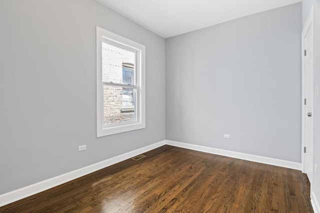 unfurnished room with baseboards, dark wood finished floors, and visible vents