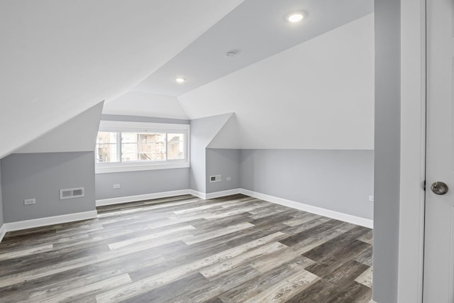 additional living space featuring baseboards, visible vents, wood finished floors, and lofted ceiling