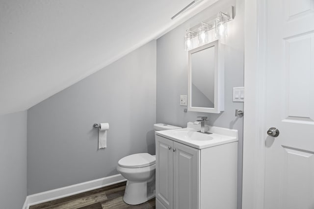 half bath featuring vanity, toilet, baseboards, wood finished floors, and lofted ceiling