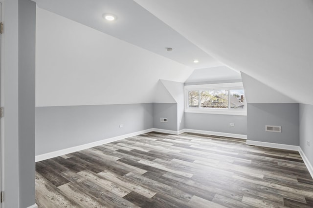 additional living space featuring baseboards, vaulted ceiling, wood finished floors, and visible vents