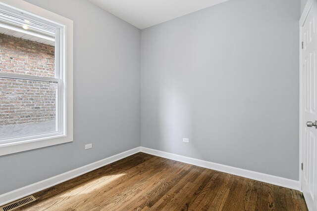 empty room with visible vents, dark wood-style flooring, and baseboards