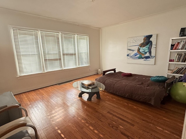 bedroom with wood-type flooring, visible vents, and ornamental molding