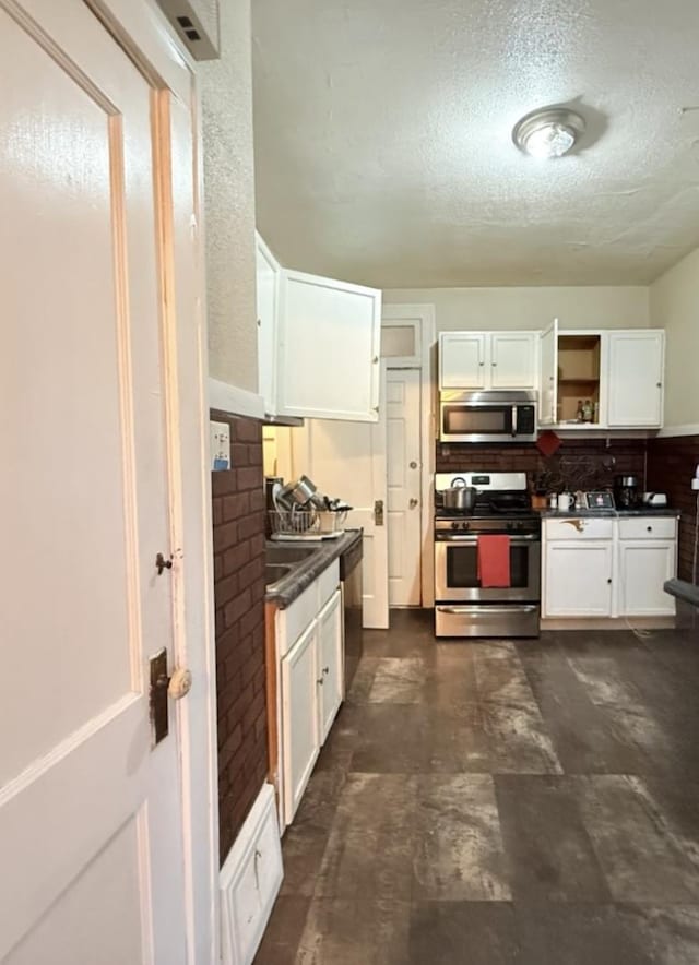 kitchen with open shelves, dark countertops, a textured ceiling, white cabinetry, and appliances with stainless steel finishes